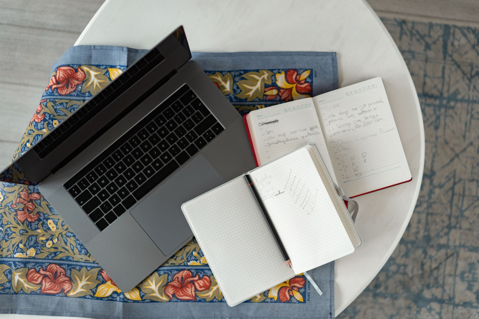 Laptop and open notebooks with handwritten training notes on a table